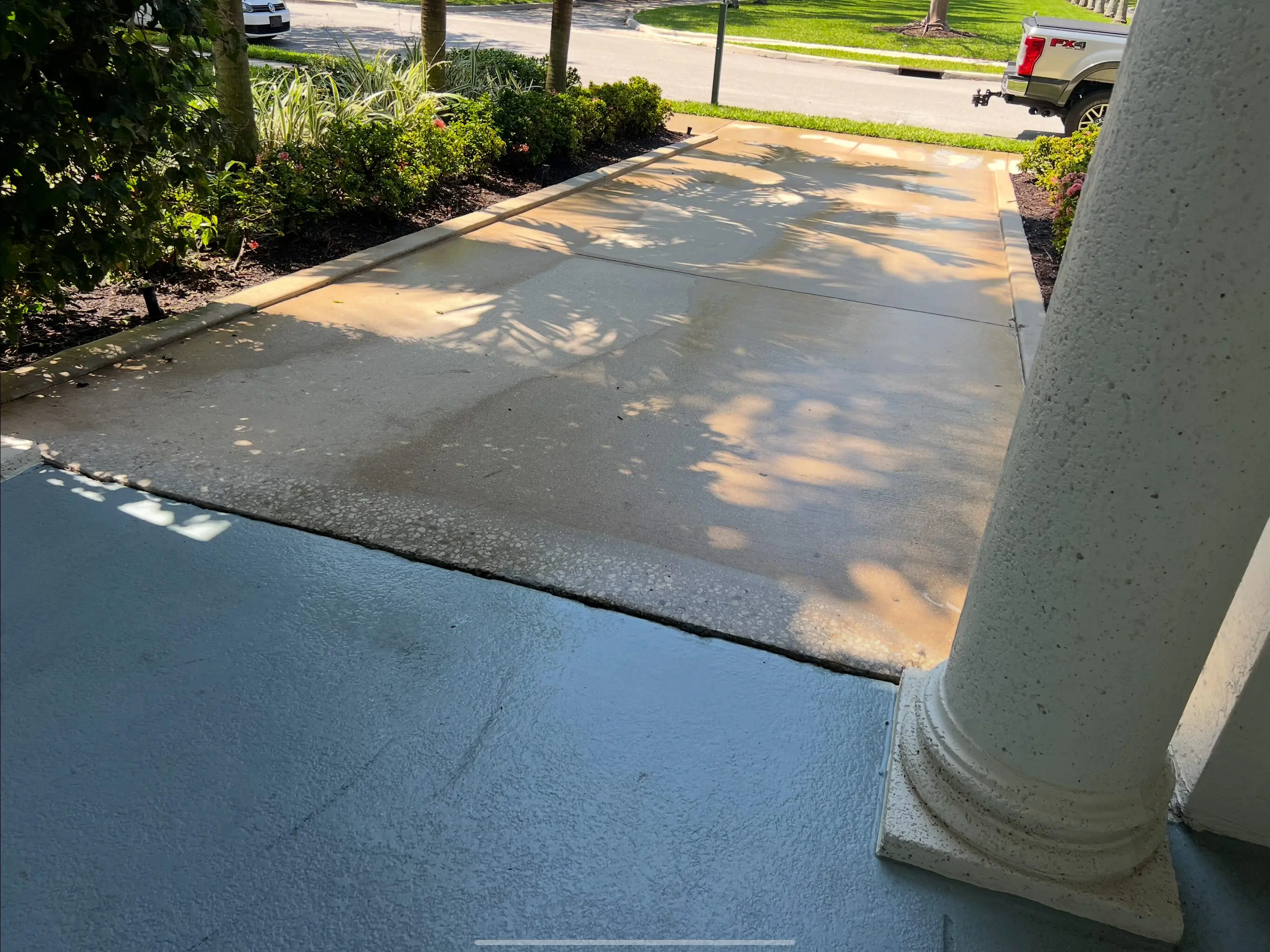 A driveway with concrete and grass on the side.